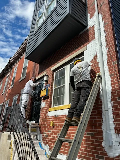 Professional painters from A.v. Paint & Design enhance a brick home's exterior in Philadelphia, PA with expert painting services.