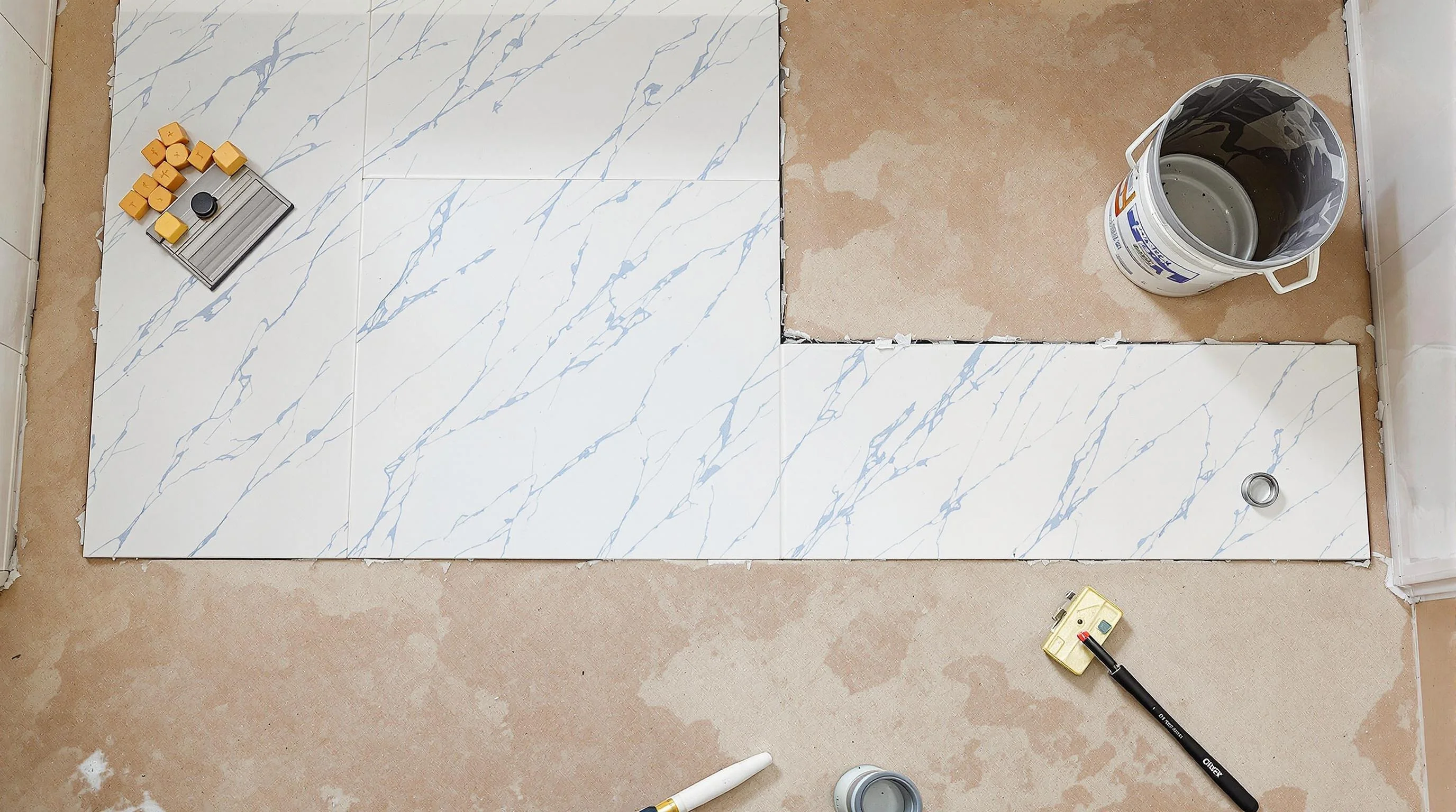 "Amayesing Floors installation with white marble tile, tools, and materials showcasing quality flooring solutions."